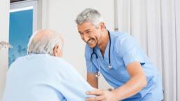 Why Having the Right Point of Care (POC) Devices is Essential for CMS’s New Patient Driven Payment Model (PDPM) Pioneer healthcare man in blue shirt with patient nurse with resident male nurse and male resident